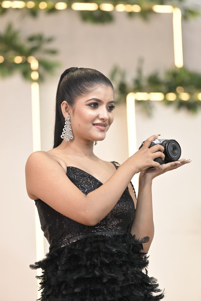 Portrait of a stylish woman holding a camera at a glamorous indoor event.